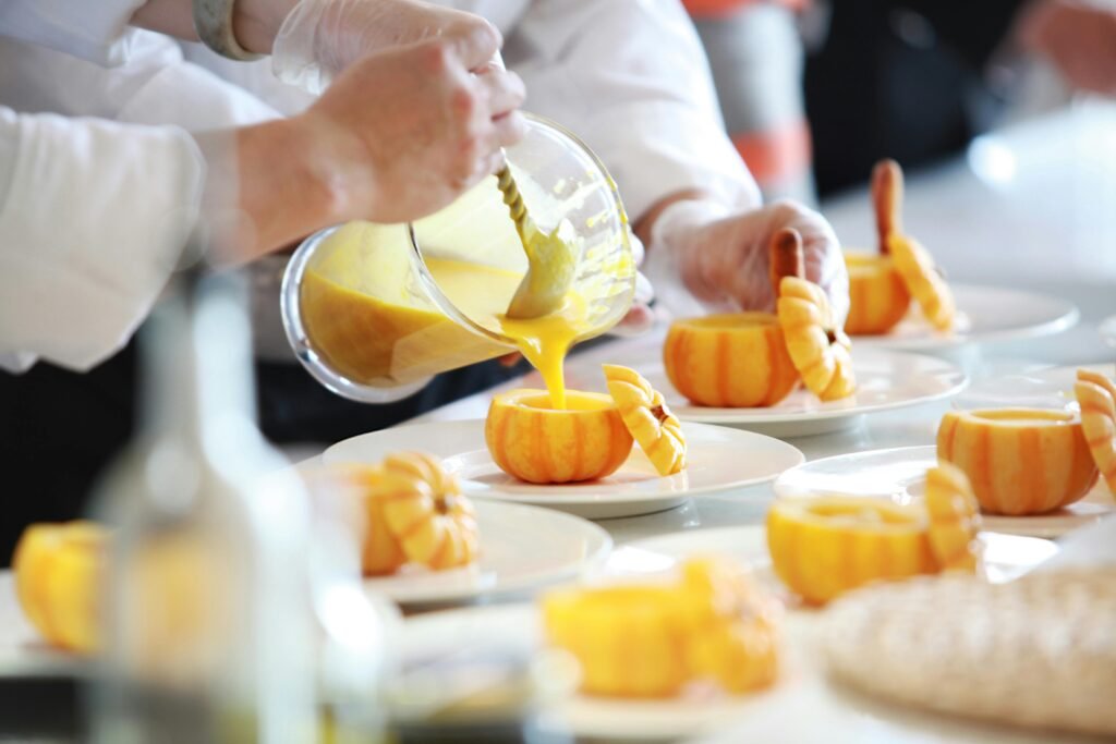 pexels-photo-671956-671956 Chef performing culinary artistry by pouring vibrant pumpkin soup in decorative pumpkins.