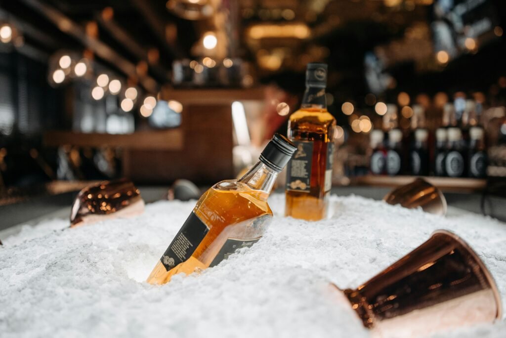 pexels-photo-7518790-7518790 Whiskey bottles resting on ice, creating a refreshing bar ambiance with warm lighting.