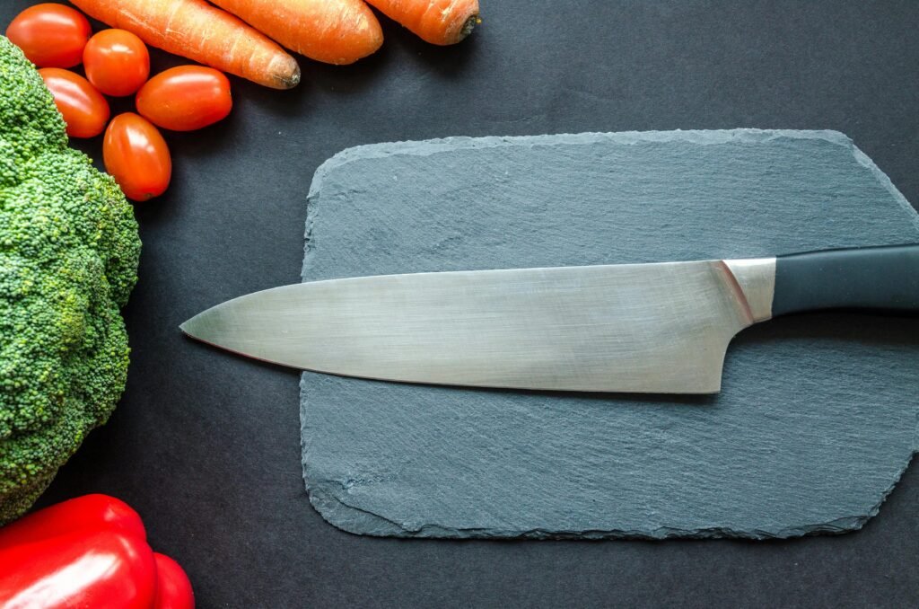 pexels-photo-952478-952478 Close-up of fresh vegetables with a chef's knife on a rustic slate board.