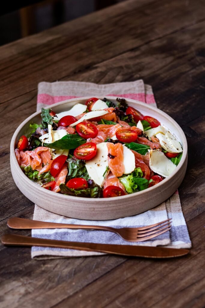 pexels-photo-15735983-15735983 Delicious Caprese salad with smoked salmon and cherry tomatoes, served on a rustic wooden table.
