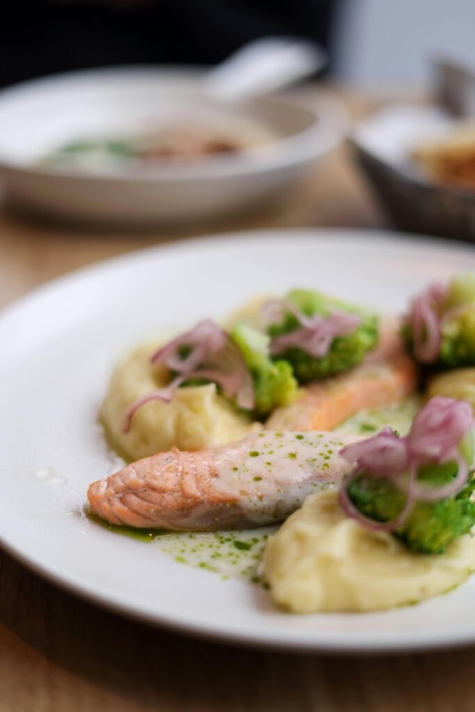 Gourmet salmon with broccoli, mashed potatoes, and garnishes served stylishly.