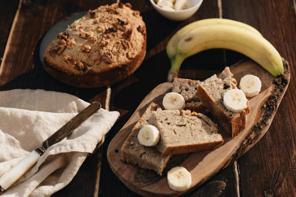 A rustic presentation of homemade banana bread with fresh bananas on a wooden board.