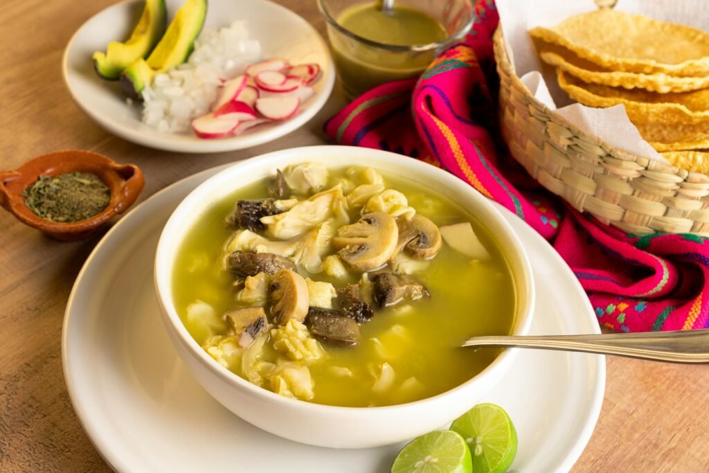 Delicious Mexican mushroom soup served with fresh garnishes, lime, and tortilla chips.