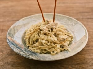 Delicious fettuccine alfredo with chicken on a rustic wooden table.