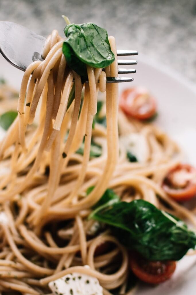 Delicious whole wheat pasta with fresh spinach, cherry tomatoes, and feta cheese in a close-up shot.