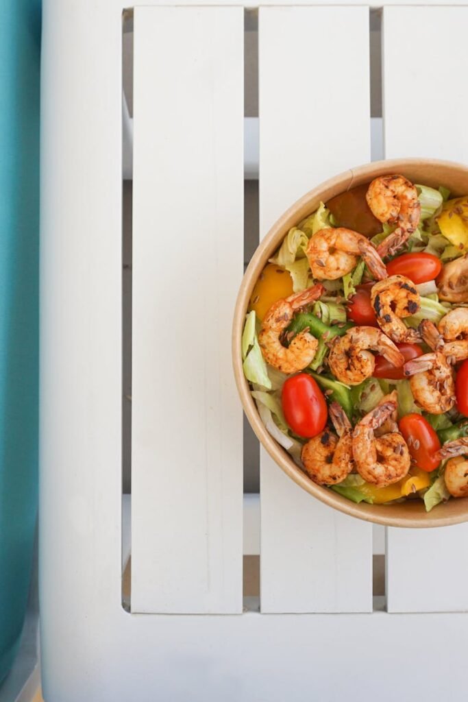 pexels-photo-27863236-27863236 Colorful shrimp salad with vegetables in a brown bowl on a white table, perfect for a healthy meal.