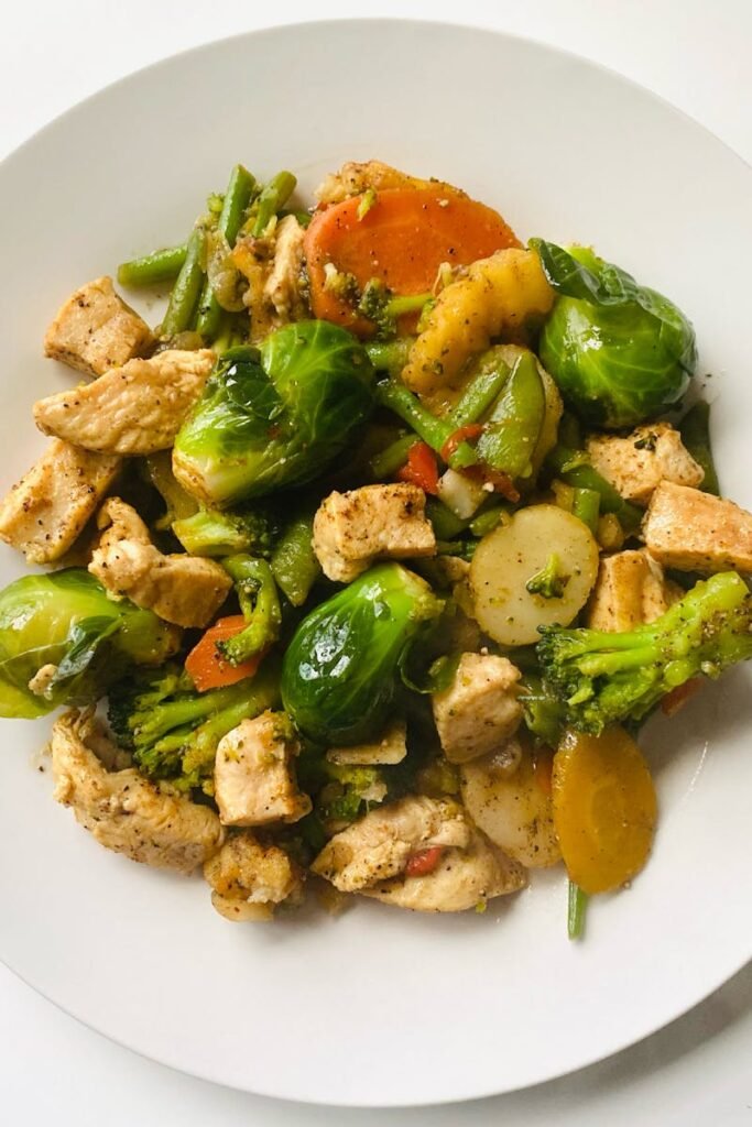 Delicious stir-fry of chicken and vegetables on a white plate for a healthy meal.