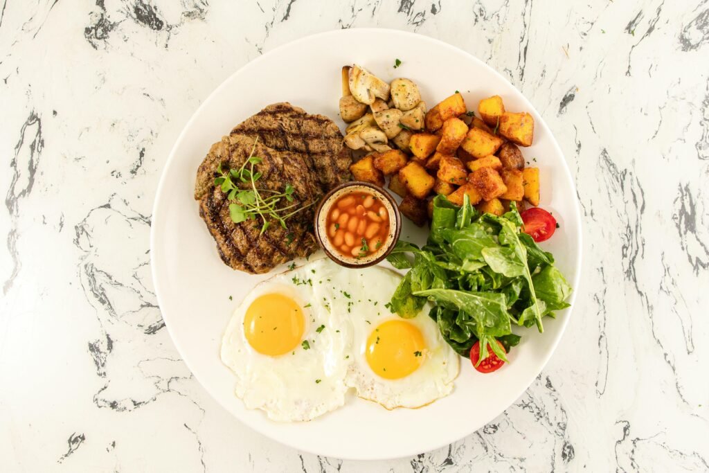 A classic English breakfast featuring fried eggs, potatoes, mushrooms, and baked beans.